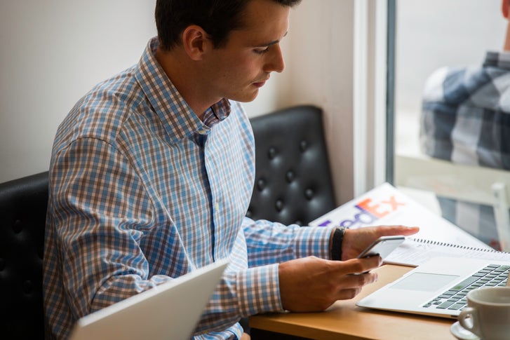 person looking at laptop with a coffee cup beside it