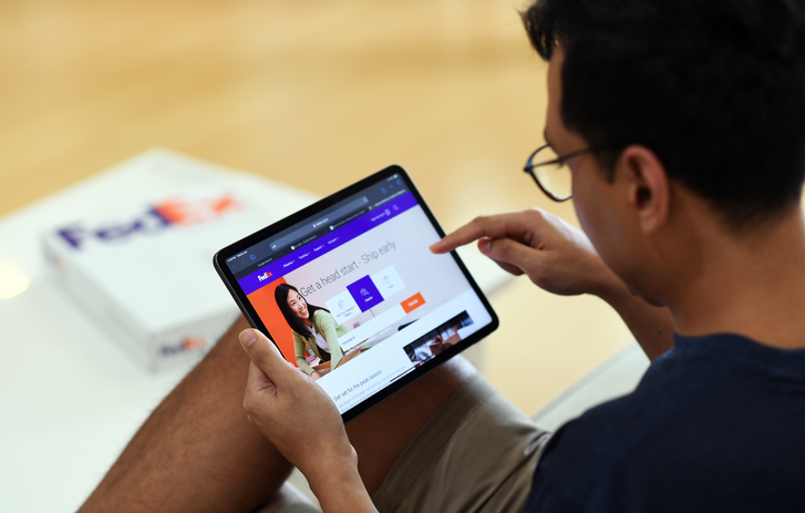 Person hält ein Tablet, auf dem die FedEx Website geöffnet ist