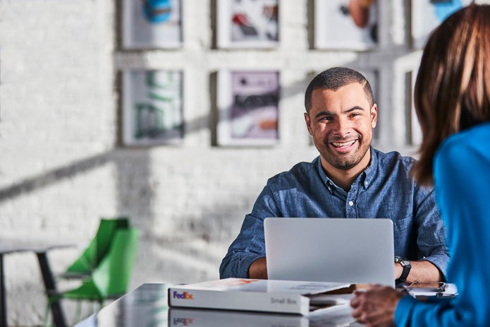 Man smiling at woman while looking up from his laptop