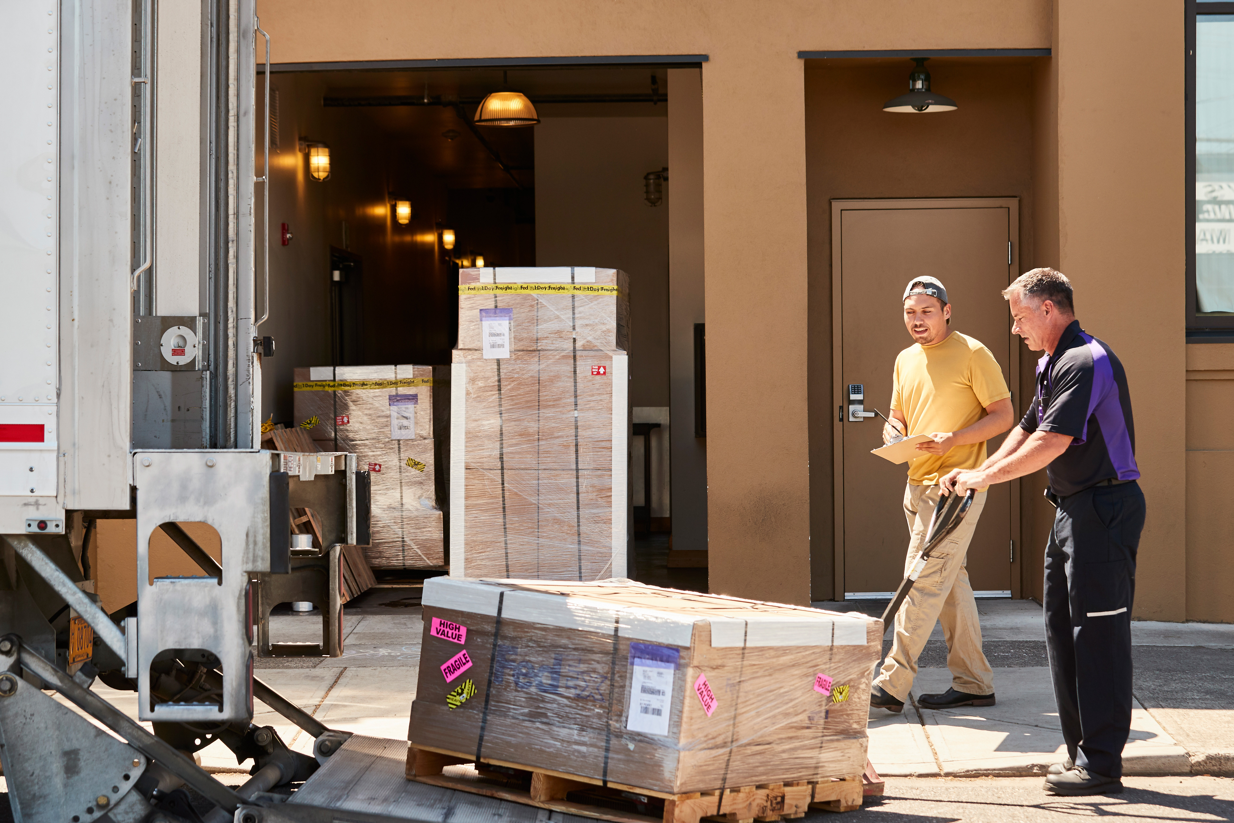 En kund pratar med en FedEx-kurir som lastar en lastpall på en FedEx lastbil