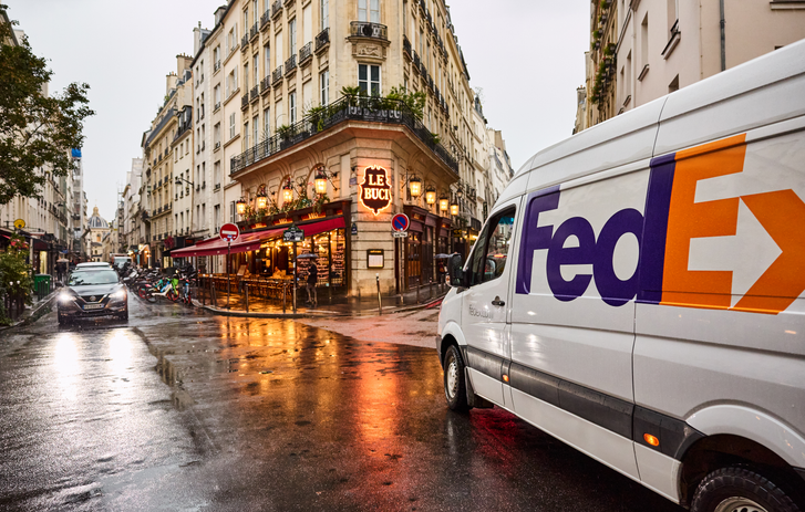 Camionnette FedEx roulant sous la pluie dans une rue parisienne