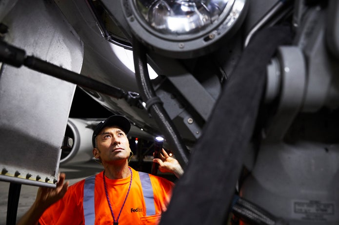 FedEx Employee looking into the landing gear of a plane