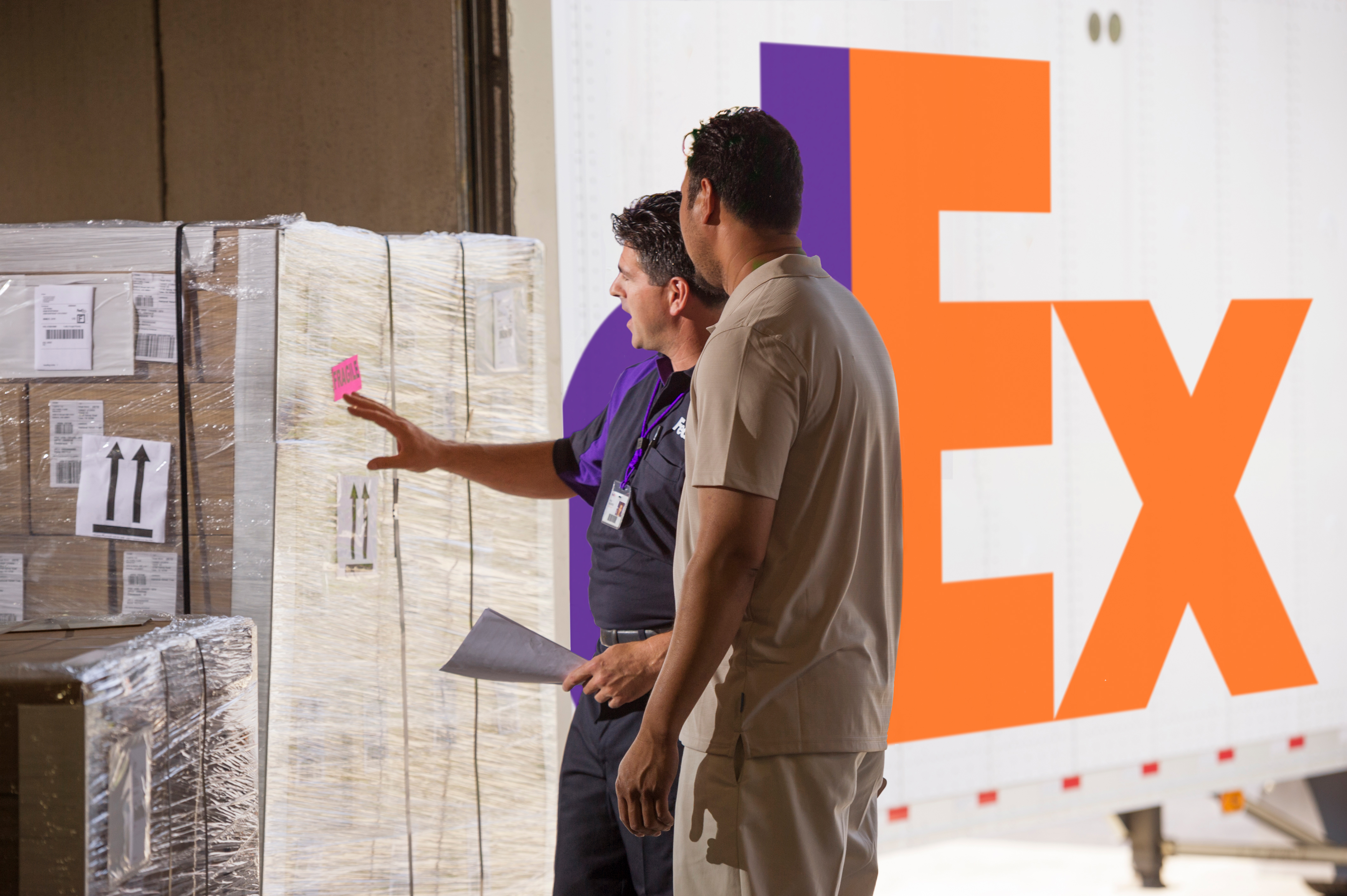 FedEx employee standing next to freight packages