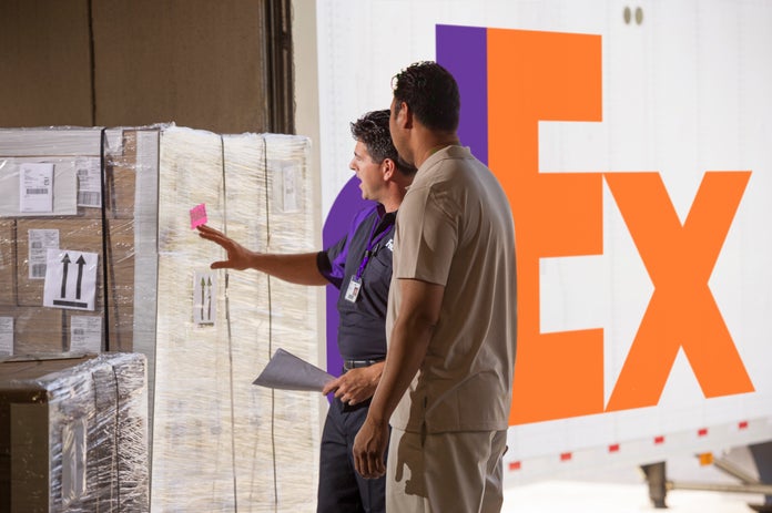FedEx employee standing next to freight packages