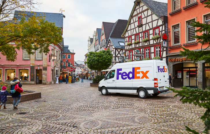 FedEx Transporter vor Geschäftsläden in einer deutschen Stadt