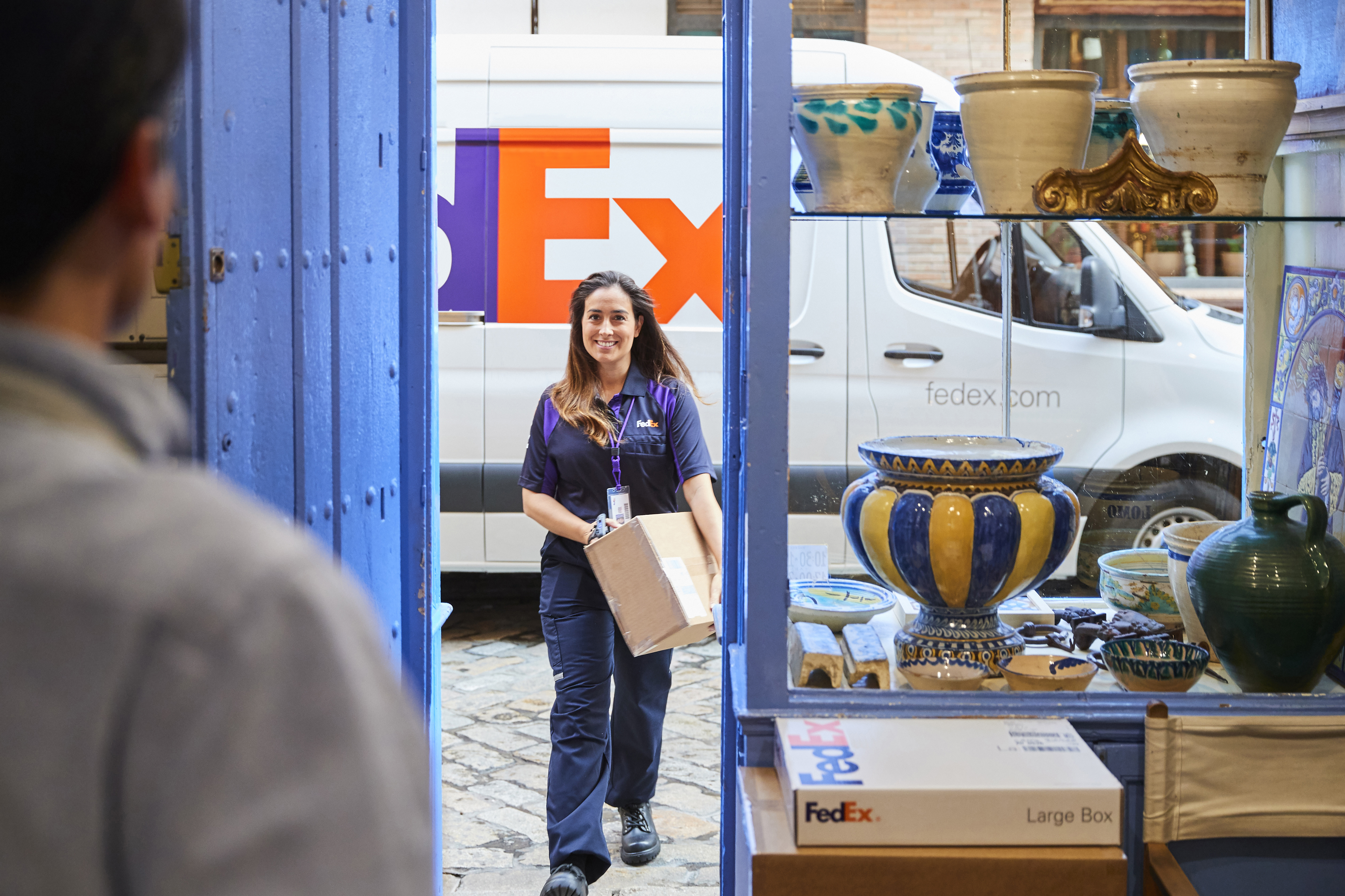 Smiling FedEx Courier walking toward open shop door