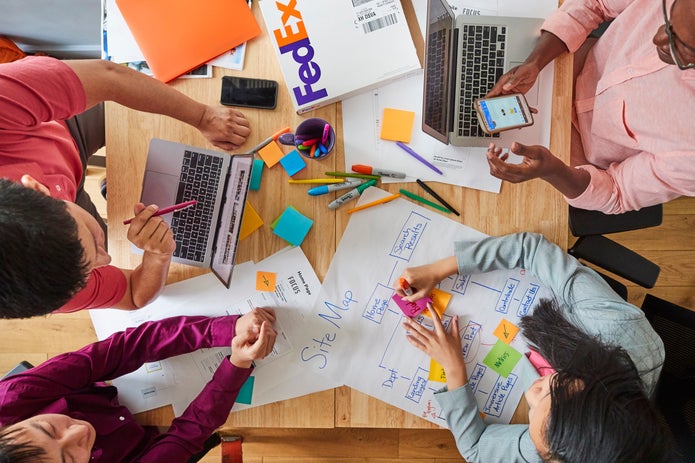 Sguardo dall'alto su 4 persone in riunione che scrivono su post-it