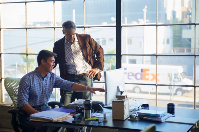 Two colleagues view information on a desktop computer