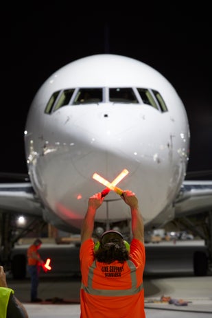 FedEx Employee stopping a plane with the orange batons