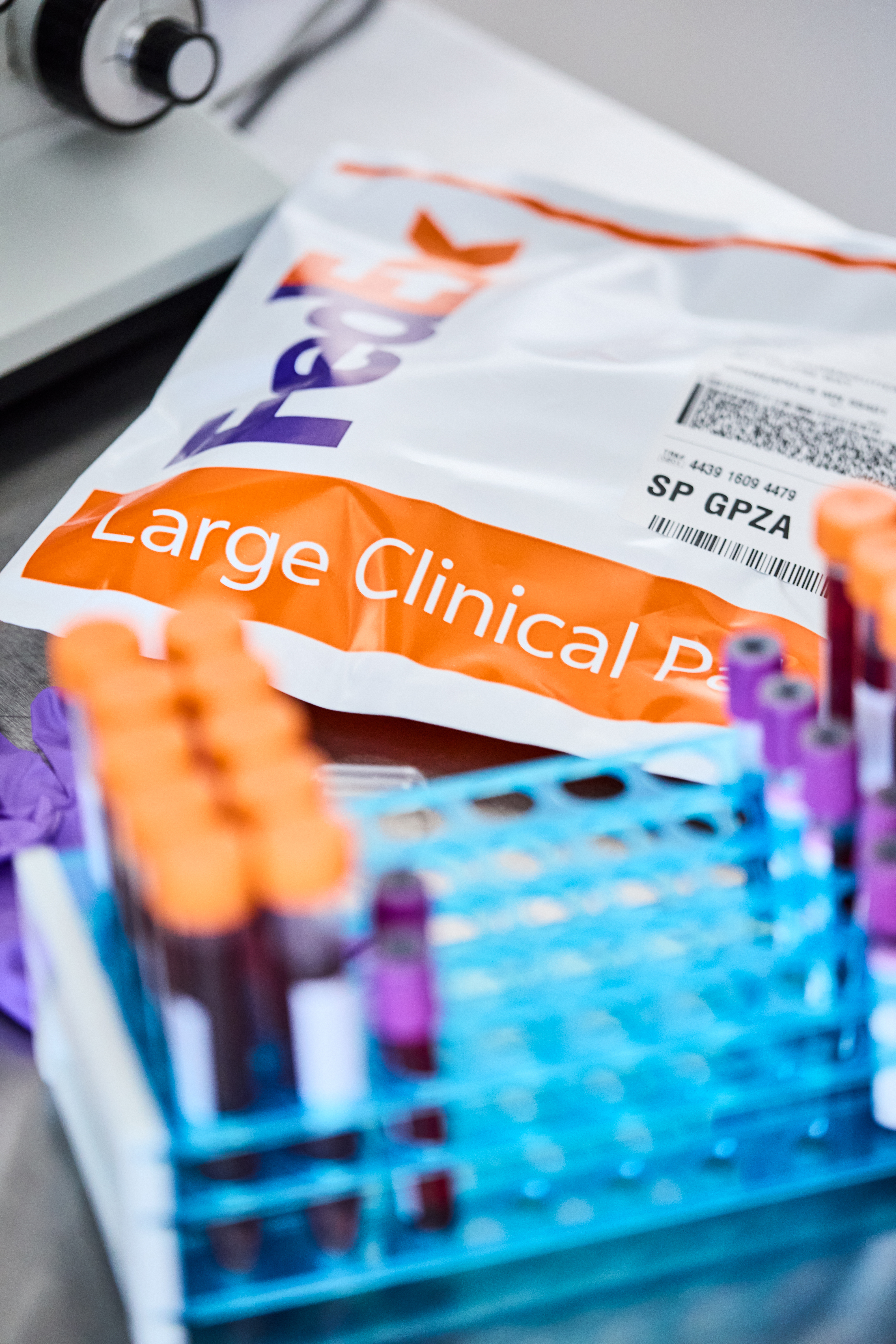 FedEx Large Clinical Pak numa mesa junto a um suporte de tubos de ensaio cheios