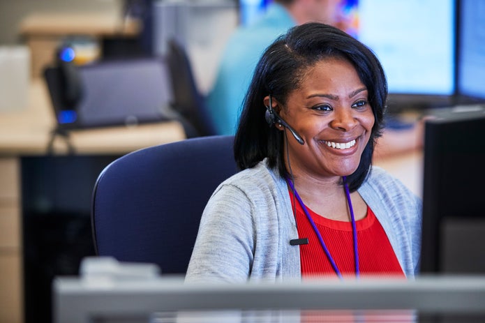 A woman wearing a headset and working at a computer.