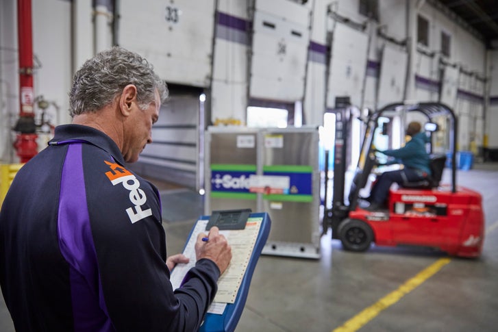 FedEx courier with Clipboard in a warehouse