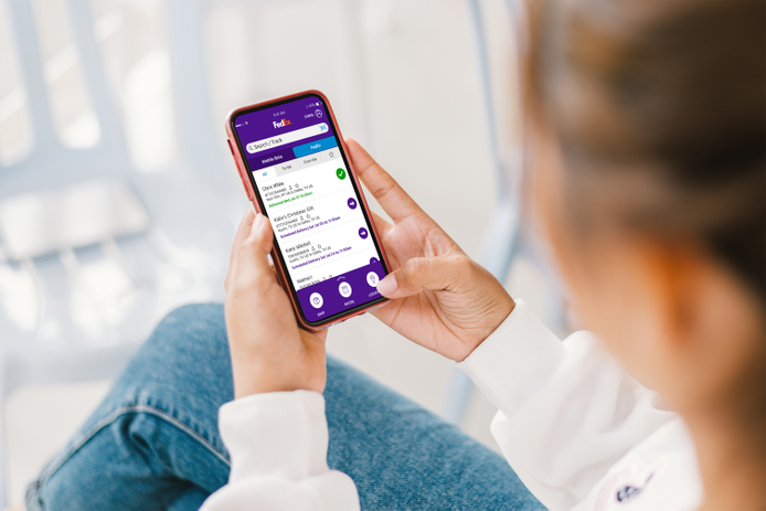Persona seduta con in mano uno smartphone con l'app FedEx aperta
