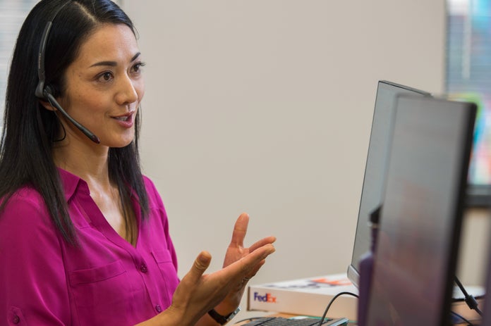 A FedEx customer support operator chats with a customer via a telephone headset.