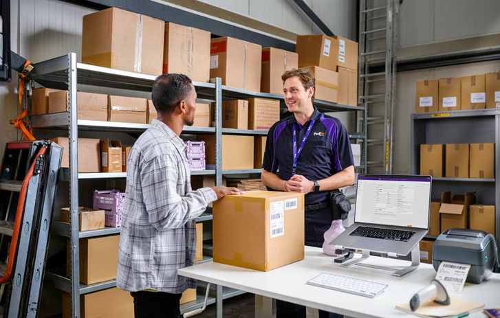 Mensajero de FedEx hablando con un cliente en un almacén