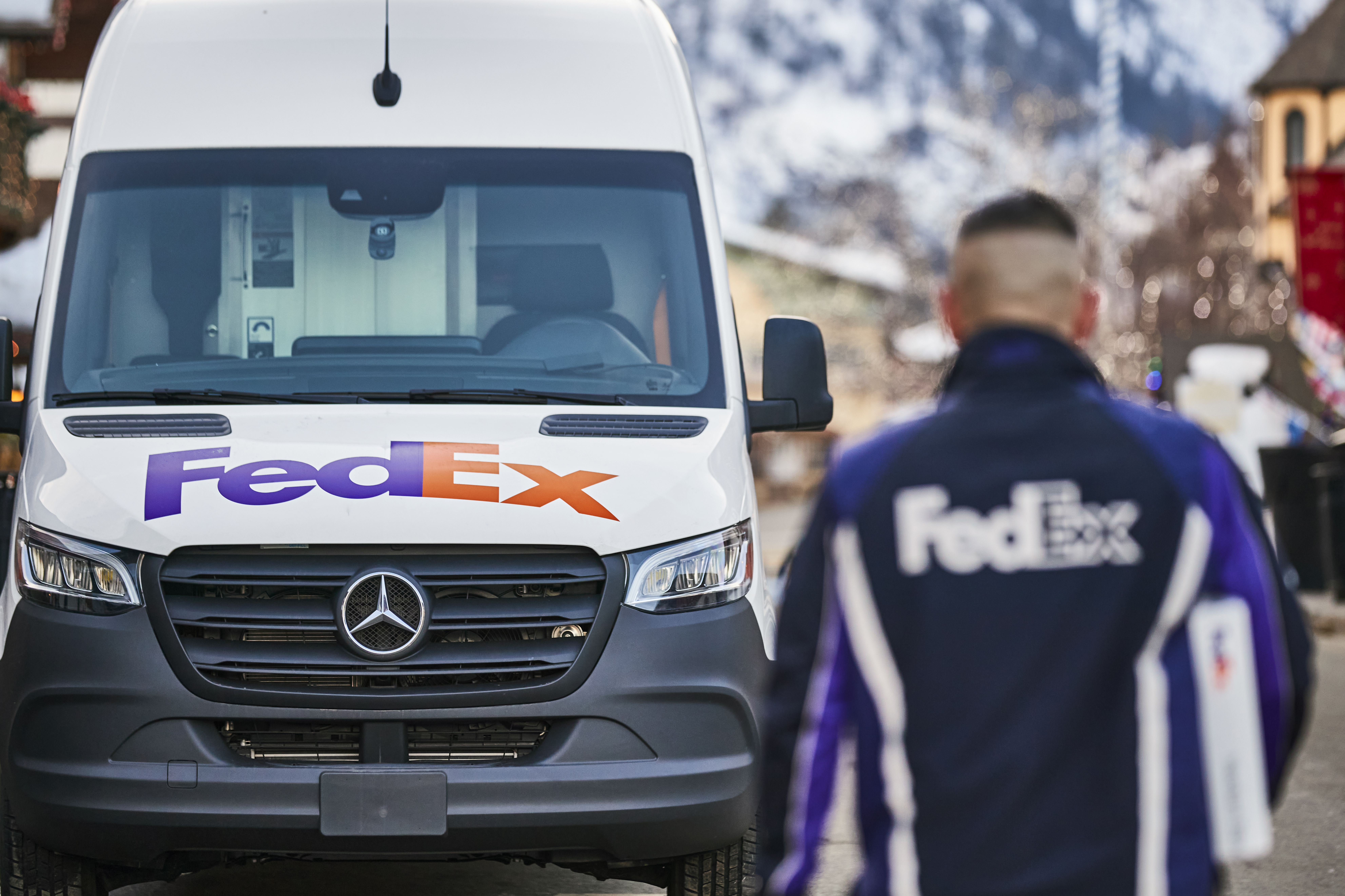 A FedEx courier walking toward a FedEx van with a box in hand