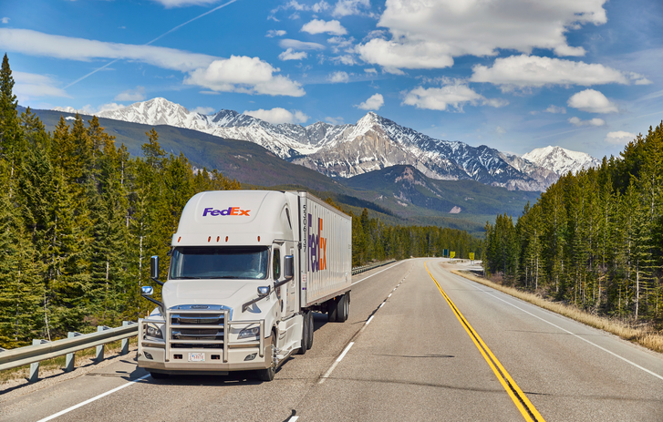 FedEx Zustellfahrzeug beim Fahren mit Bergkulisse