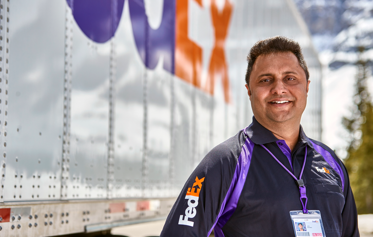 Smiling FedEx courier standing next to Truck