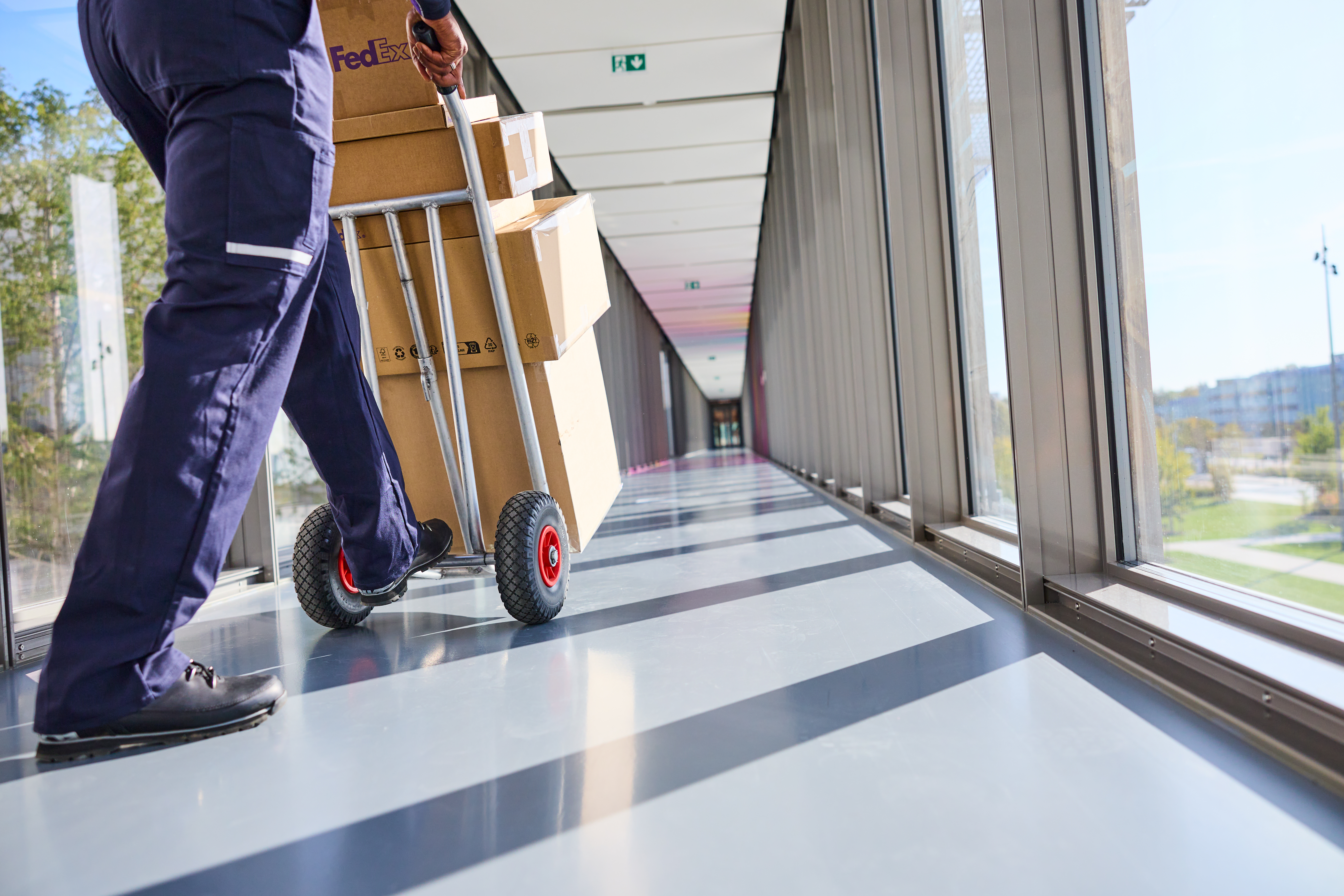 Delivery person pushing boxes down hall