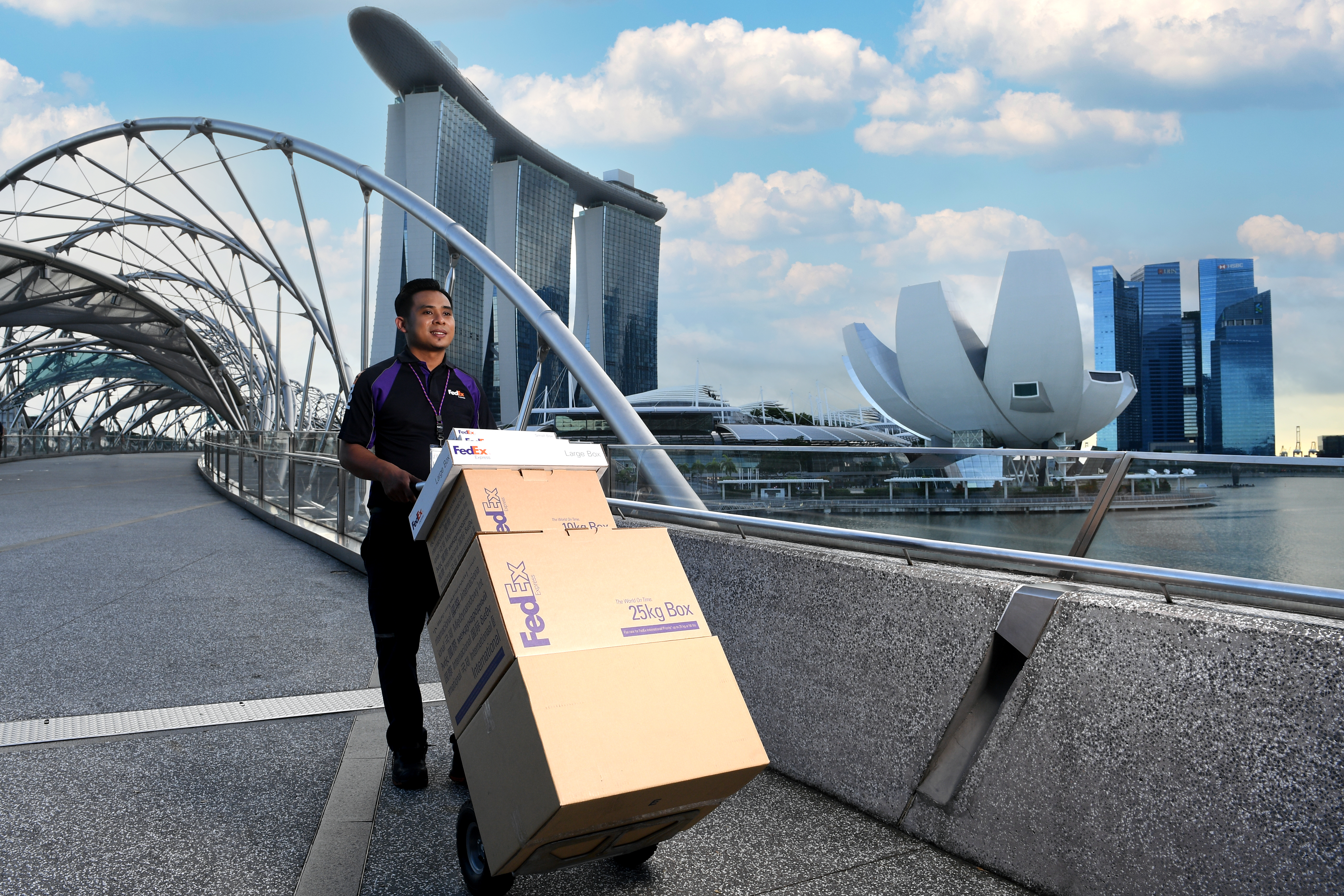 FedEx employee pushing packages on shopping cart outside