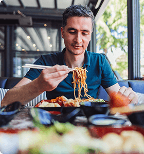 man eating noodles with chopsticks
