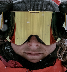 Close-up of an adventurer wearing reflective Zeal Optics goggles in snowy winter conditions.