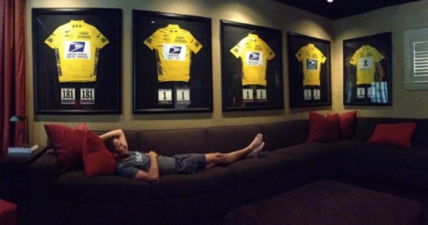 Lance Armstrong on his couch surrounded by his Tour de France jerseys