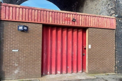 The front of an arch with a closed metal concertina door that can be pulled back fully. 
