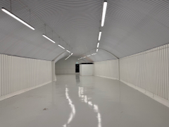 An empty arch with white lining and a WC cubicle to the back.