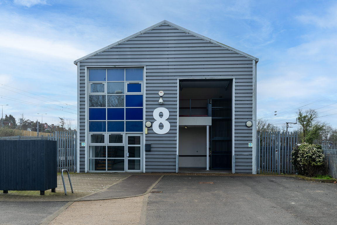 The front of a warehouse unit, with an open electric roller shutter entrance big enough for vehicle access, and a pedestrian door.