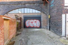 The front of an arch with a closed electric roller shutter entrance big enough for vehicle access. 