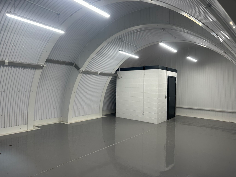 An empty arch with white lining and a WC cubicle to the back.