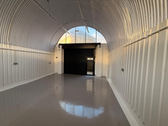 An empty arch with white lining and full height glazing to the front.