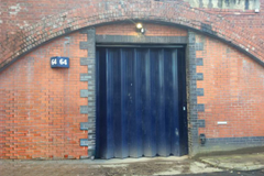 The front of an arch with a closed metal concertina door that can be pulled back fully. 