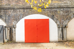 The front of an arch with a closed metal concertina door that can be pulled back fully.
