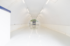 An empty arch with white lining and a WC cubicle to the back.