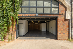 The front of an arch, with high level glazing, and an open electric roller shutter entrance big enough for vehicle access.