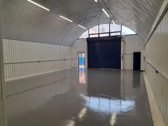 An empty arch with white lining, facing the front electric roller shutter entrance, which is closed.