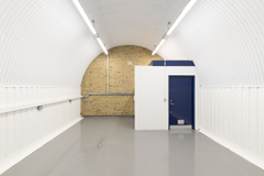 An empty arch with white lining and a WC cubicle to the back.
