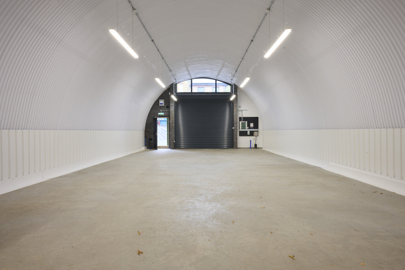 An empty arch with white lining, facing the front electric roller shutter entrance, which is closed.
