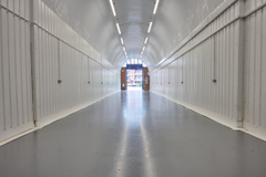 An empty arch with lining, facing the front electric roller shutter entrance, which is open.