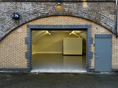 The front of an arch with an open electric roller shutter entrance big enough for vehicle access, and separate pedestrian door.