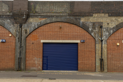 The front of an arch with a closed electric roller shutter entrance big enough for vehicle access. 