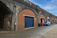 The front of an arch, with high level glazing, a closed electric roller shutter entrance big enough for vehicle access, and a pedestrian door.