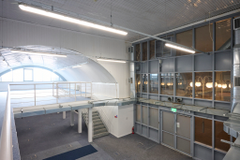 An arch with white lining and a ground floor level and a mezzanine level, connected by stairs.