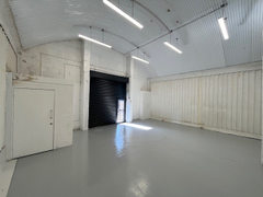An empty arch with white lining and a WC cubicle to the front.