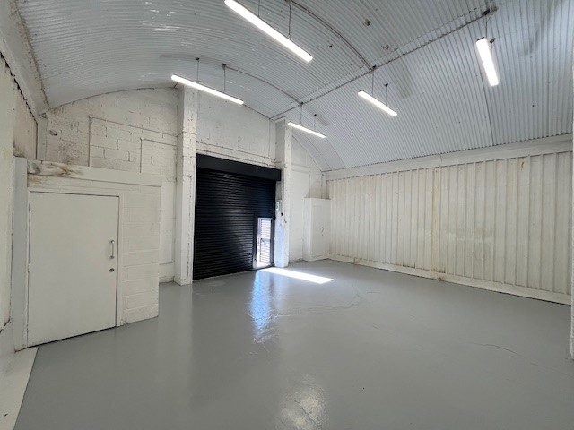 An empty arch with white lining and a WC cubicle to the front.