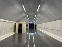 An empty arch with white lining, facing the front electric roller shutter entrance, which is closed. There is a WC cubicle at the front of the arch.