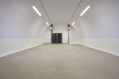 An empty arch with white lining and a fire escape door at the back.