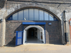 The front of an arch, with high level glazing, an open electric roller shutter entrance big enough for vehicle access, and a pedestrian door.